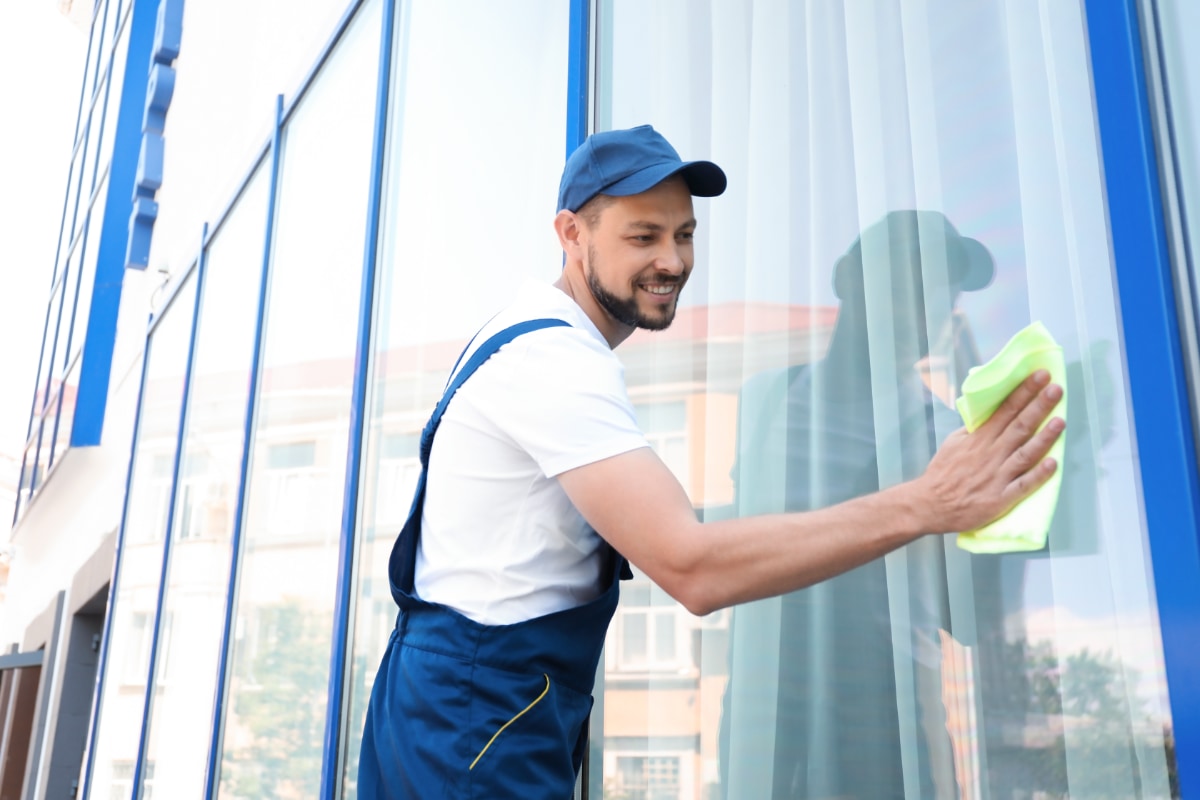 man wiping down an exterior window with a cleaning cloth